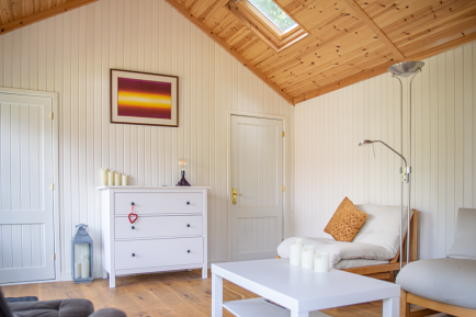 Crane Garden Room with toilet - interior living area Bright garden room interior with vaulted timber ceiling, rooflight, panelled walls, wooden flooring and, contemporary seating and two internal doors on a partition wall.